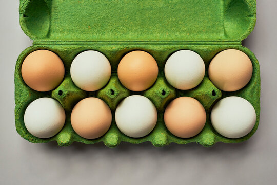 View from above of alternating organic brown and white eggs in vibrant green carton