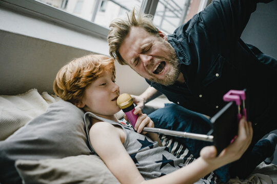 Father and son with smartphone and microphone at home