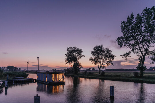 Illuminated houseboat on Yser River at sunset