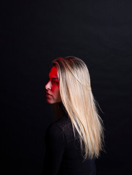 Model with blonde hair illuminated by red light on dark background