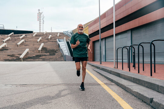 Determined senior man running on footpath