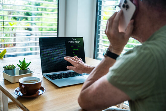 Man talks on smartphone and points at data security on notebook