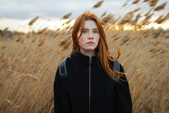 Portrait of a backpacker standing in a field of reeds at sunset