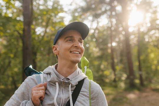 Smiling man with backpack hikes through a sunny forest