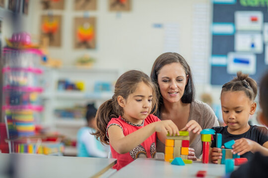 Pre-school teacher playing with girls in kindergarten