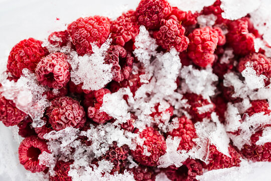 close up of frozen raspberries with ice crystals in clear container