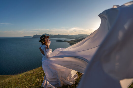 Woman dress mountain, woman wearing elegant white dress standing on a grassy hill overlooking the ocean at sunset with copy space