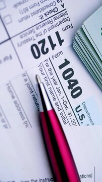 US Tax Forms and Dollar Bills. Close-up view of income tax documents with cash and a red pen during smooth camera movement.