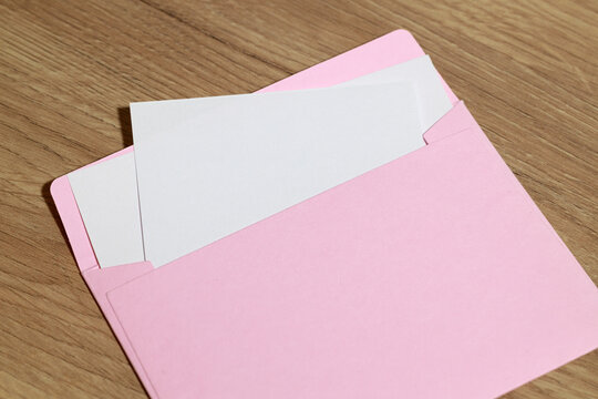 Pink envelope with blank white cards on a wooden table surface