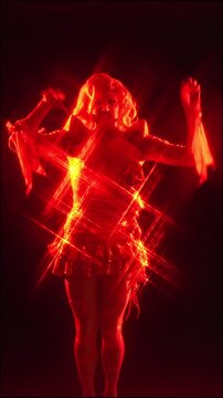Drag queen performing on stage in a sparkly red light