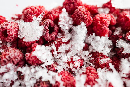 close up of frozen raspberries with ice crystals in clear container