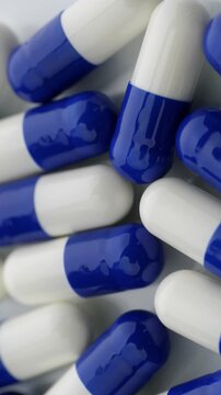 Blue and White Capsules. Macro view of glossy medicine capsules with smooth camera movement.