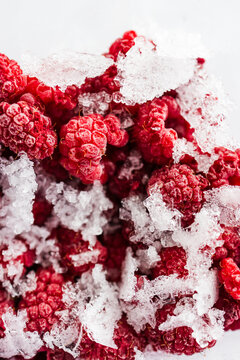 close up of frozen raspberries with ice crystals in clear container