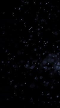 Floating Particles on Dark Background. Soft glowing particles drift through darkness, creating an atmospheric abstract bokeh effect.