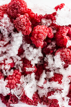 close up of frozen raspberries with ice crystals in clear container
