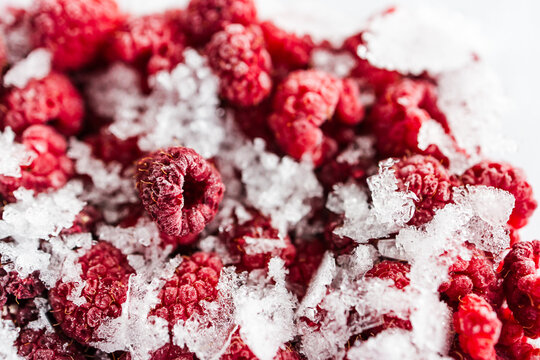 close up of frozen raspberries with ice crystals in clear container