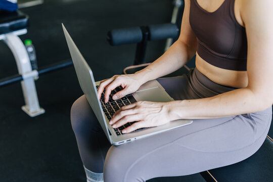 Healthy working woman business working in sport fitness gym on laptop computer closeup shot