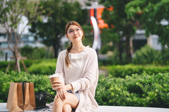 Single adult business asian woman holding coffee cup relax sitting with shopping bag on black friday holidays sale city people lifestyle