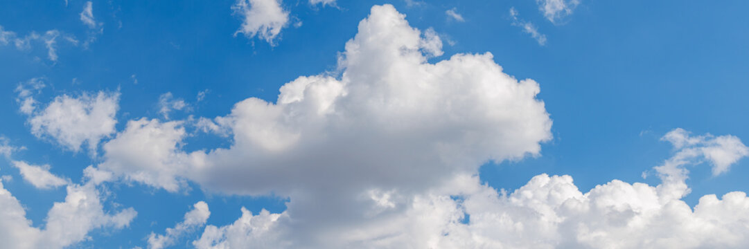 Clouds drift in the blue sky under bright sunlight during midday hours, banner