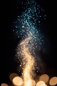Golden sparks rising into a fountain of blue firework light