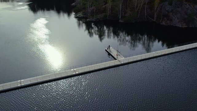 Floating bridge Stora Delsjon flytbro in the Delsjoomradet nature reserve. Wooden pedestrian walkway over water in Sweden.