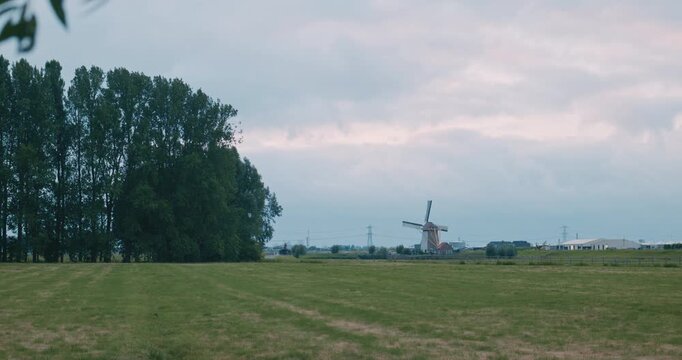 vast green field meadow landscape view with windmill traditional architecture cloudy sky clouds tree line open rural countryside serene pastoral scenery grassy meadow