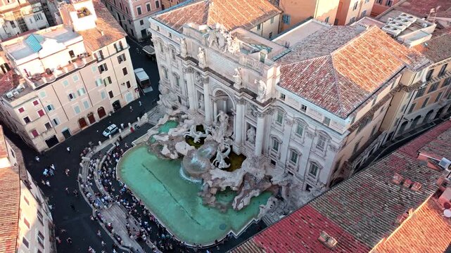 Fontana di Trevi fills the frame as a drone glides above the crowded basin and terracotta rooftops in warm afternoon light.