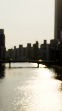 夕暮れ時の太陽に照らされてキラキラ輝く道頓堀川の水面のスローモーション。アウトフォーカス映像