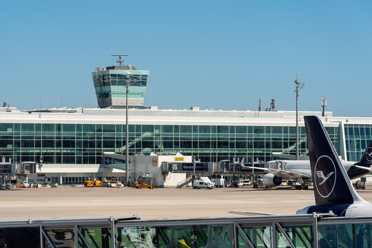 Modern Airport Terminal and Control Tower with Lufthansa Aircraft on the Apron at Daytime in Munich, Germany. 