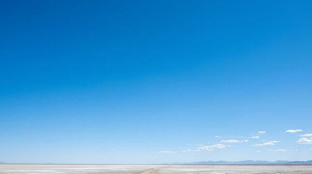 Vast Blue Sky Over a Flat Horizon with Distant Mountains and Clouds.
