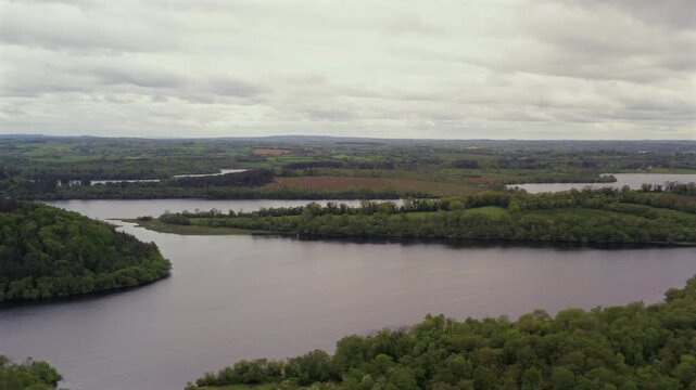 Wide aerial pan of Lough Oughter with lush green forest landscapes surrounding lake. County Cavan