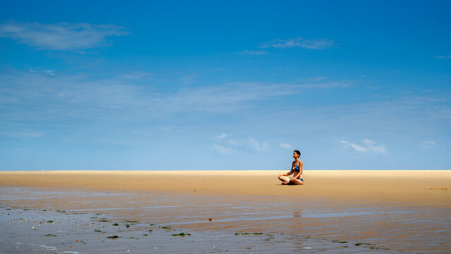 Femme assise en position de yoga face &agrave; l'oc&eacute;an atlantique sur la plage de la pointe Espagnole dans le d&eacute;partement de Charente Maritime