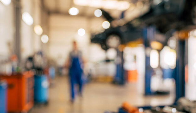 A blurred image of a busy automotive workshop. Mechanics are working on vehicles in a well-equipped garage environment, showcasing equipment and tools.