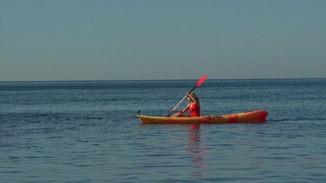 Kayak, woman, ocean Paddling solo kayak on vast blue water enjoying summer vacation watersports activity