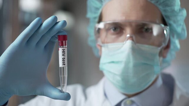 Laboratory technician holding a blood sample tube labeled HIV test.