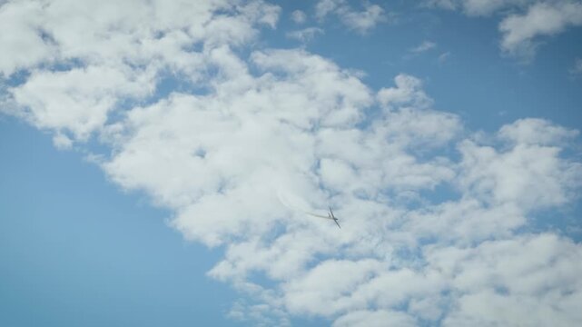 A white smoke loop pattern created by an aerobatic airplane in a clear blue sky with soft white clouds.