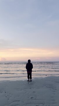 Person Standing on Beach at Sunset