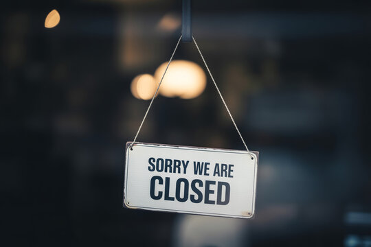 Close up view of hanging wooden sign displaying text message stating sorry we are closed.