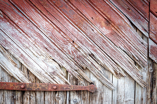 Old rotten wooden door close up with handmade iron hinge. Architectural detail background.
