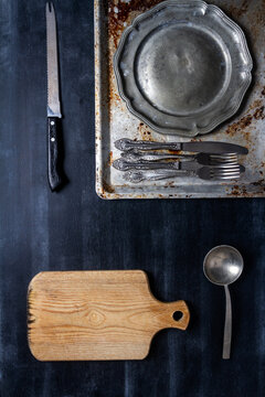 Old various kitchen utensils on black chalkboard background. Food themed flat lay.