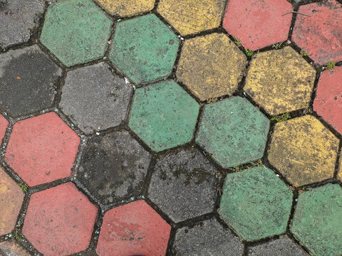 Textured red and green hexagonal stone pavers create a weathered pavement surface Abstract Background Concept Design