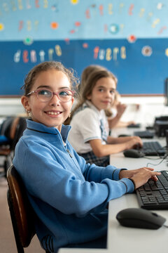 Girls using desktop computer in school computer lab