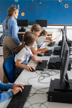 Teacher supervising students during computer class at school