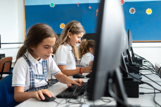 Girls using desktop computer in school computer lab