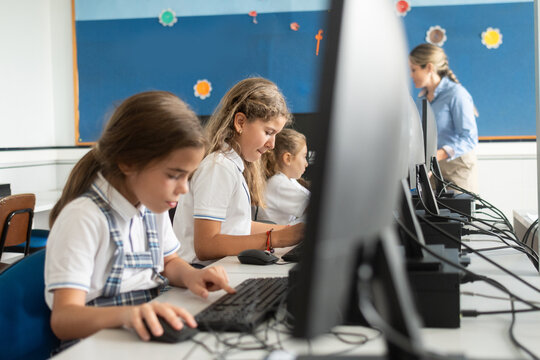 Girls using desktop computer in school computer lab