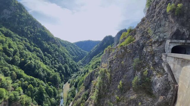 Deep Gorge Below Vidraru Dam in the Carpathian Mountains, Romania. Concept of mountain engineering, dramatic terrain, hydropower infrastructure and travel.