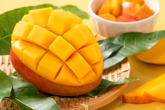 Fresh ripe cut mango fruit slices on yellow background.