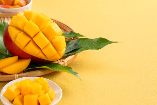 Fresh ripe cut mango fruit slices on yellow background.
