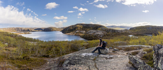 Fototapeta premium Panoramic view Woman sitting on mountain Oretoppen ( norwegian Øretoppen ) on South Varanger, in Finnmark County, Norway