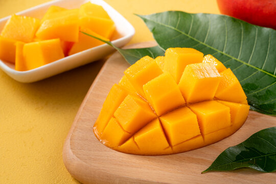 Fresh ripe cut mango fruit slices on yellow background.